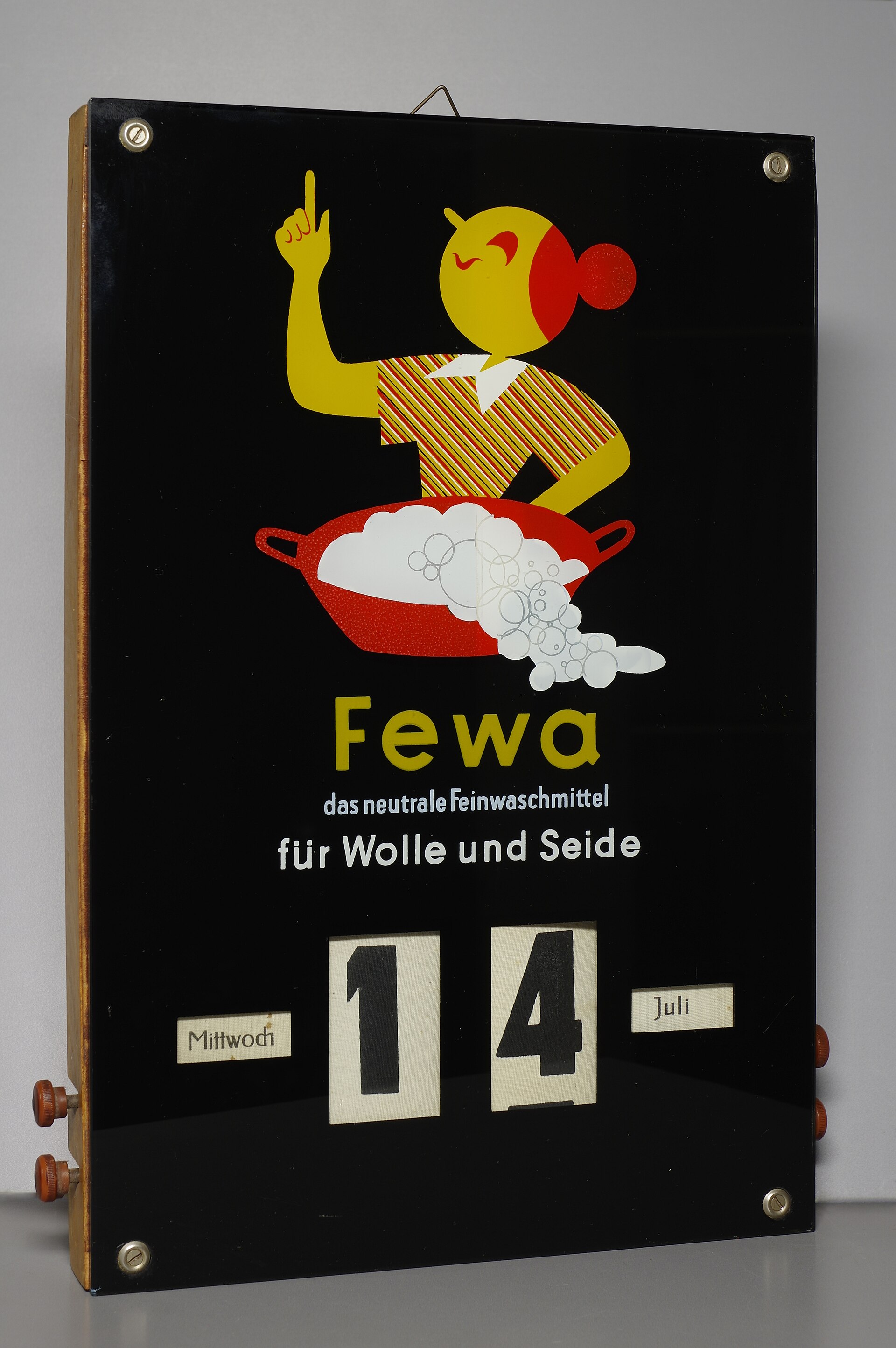 A black enamel advertising wall calendar with wooden knobs at the sides and hand-set cards showing the weekday, date and month.