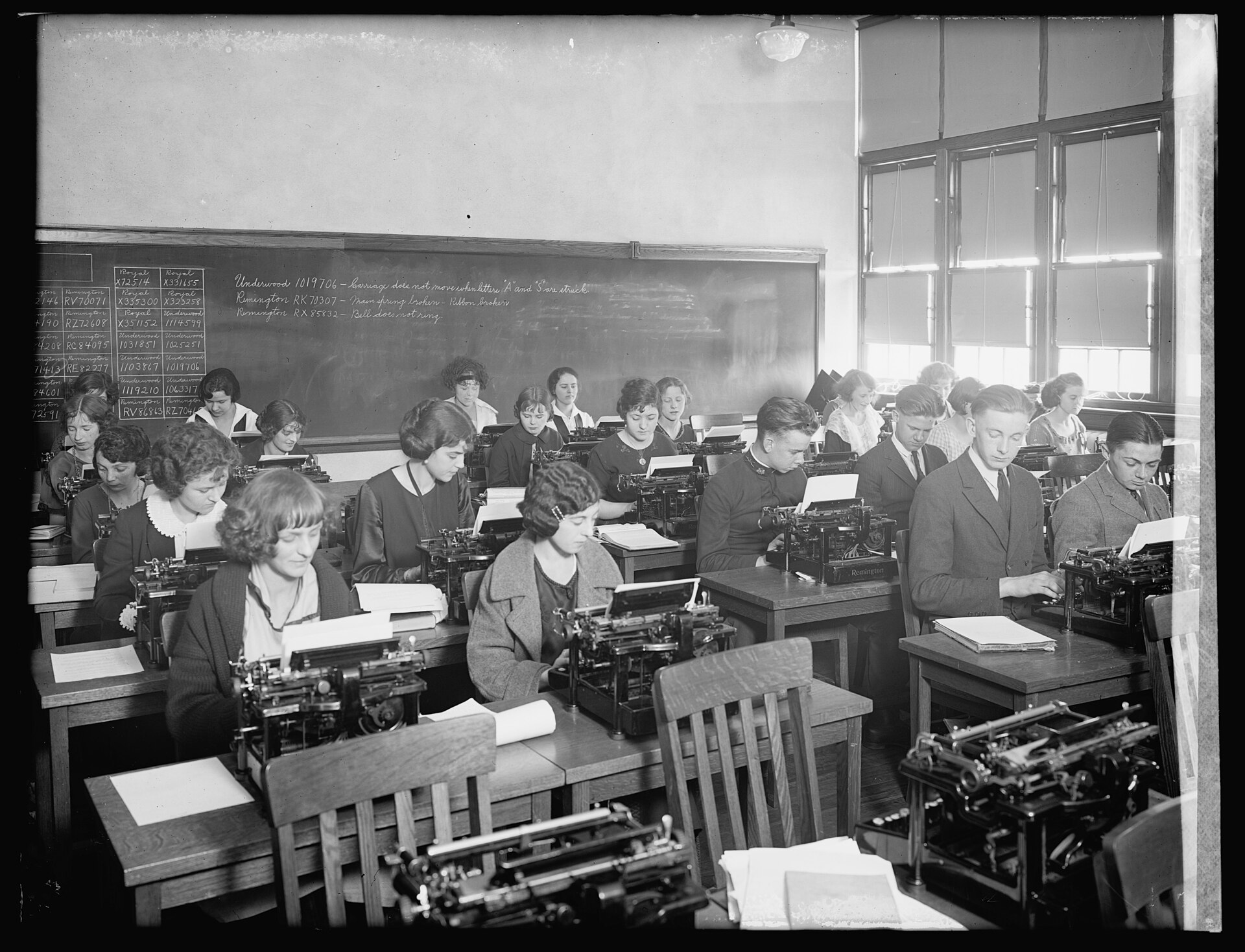 Rows of students at typewriters in an early twentieth-century classroom.