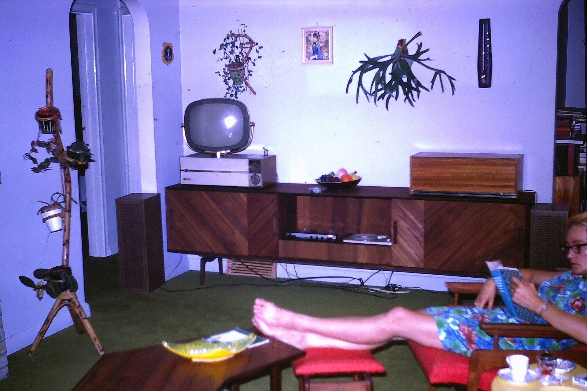 A 1960s living room with a television set on a stand, chairs turned towards it.