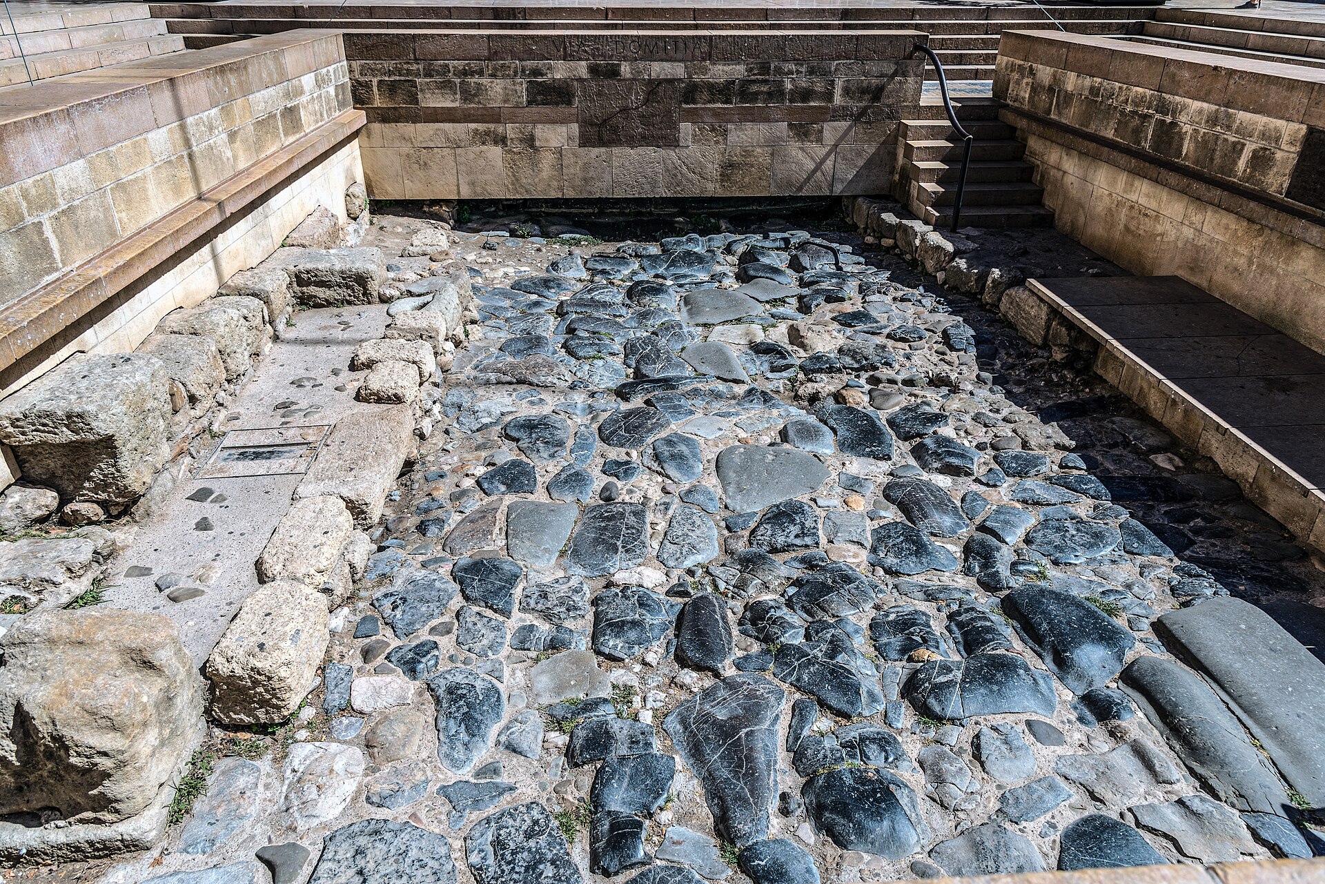 A stretch of Roman paved road with worn, irregular stone blocks.