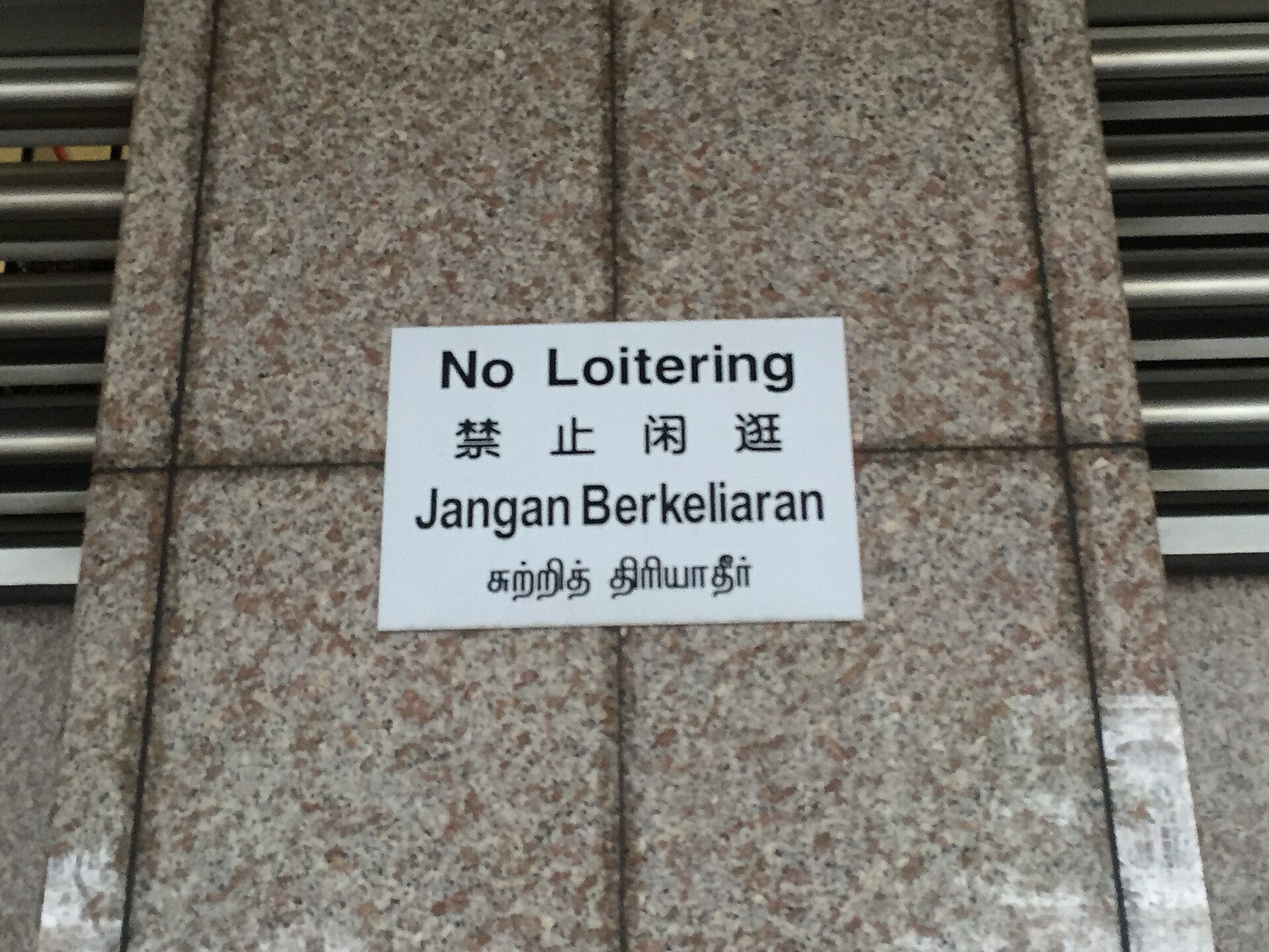 A public notice in Singapore repeated in four languages on one plate.