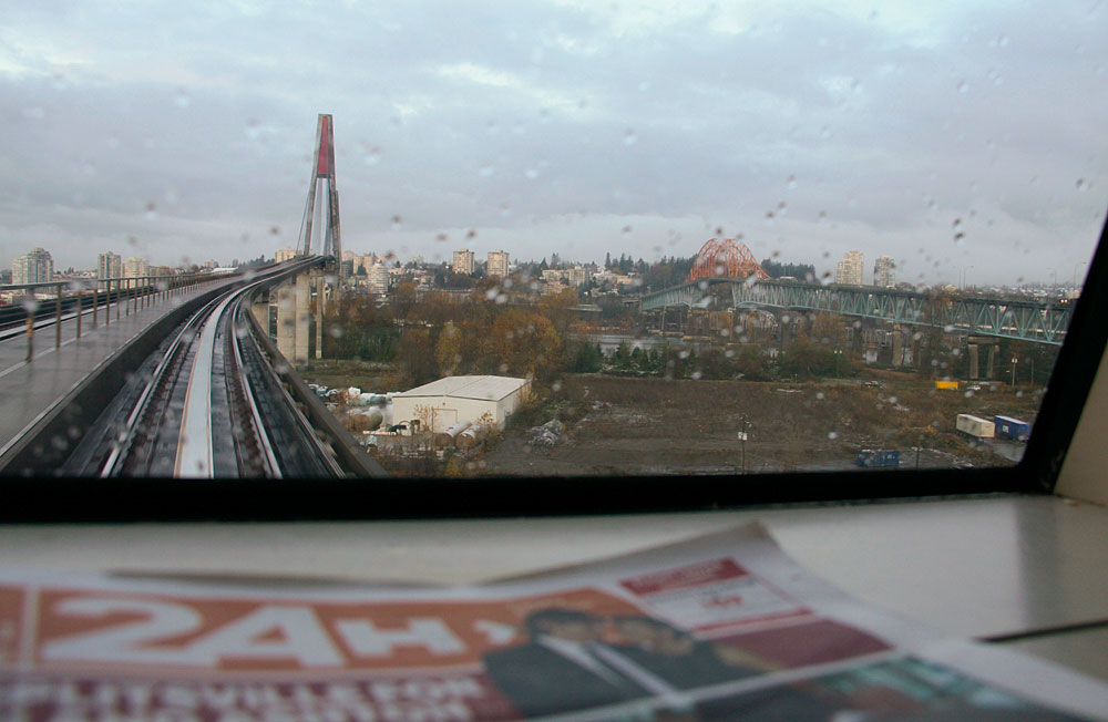 Passengers sitting in a commuter train carriage, each occupied with something in their hands.