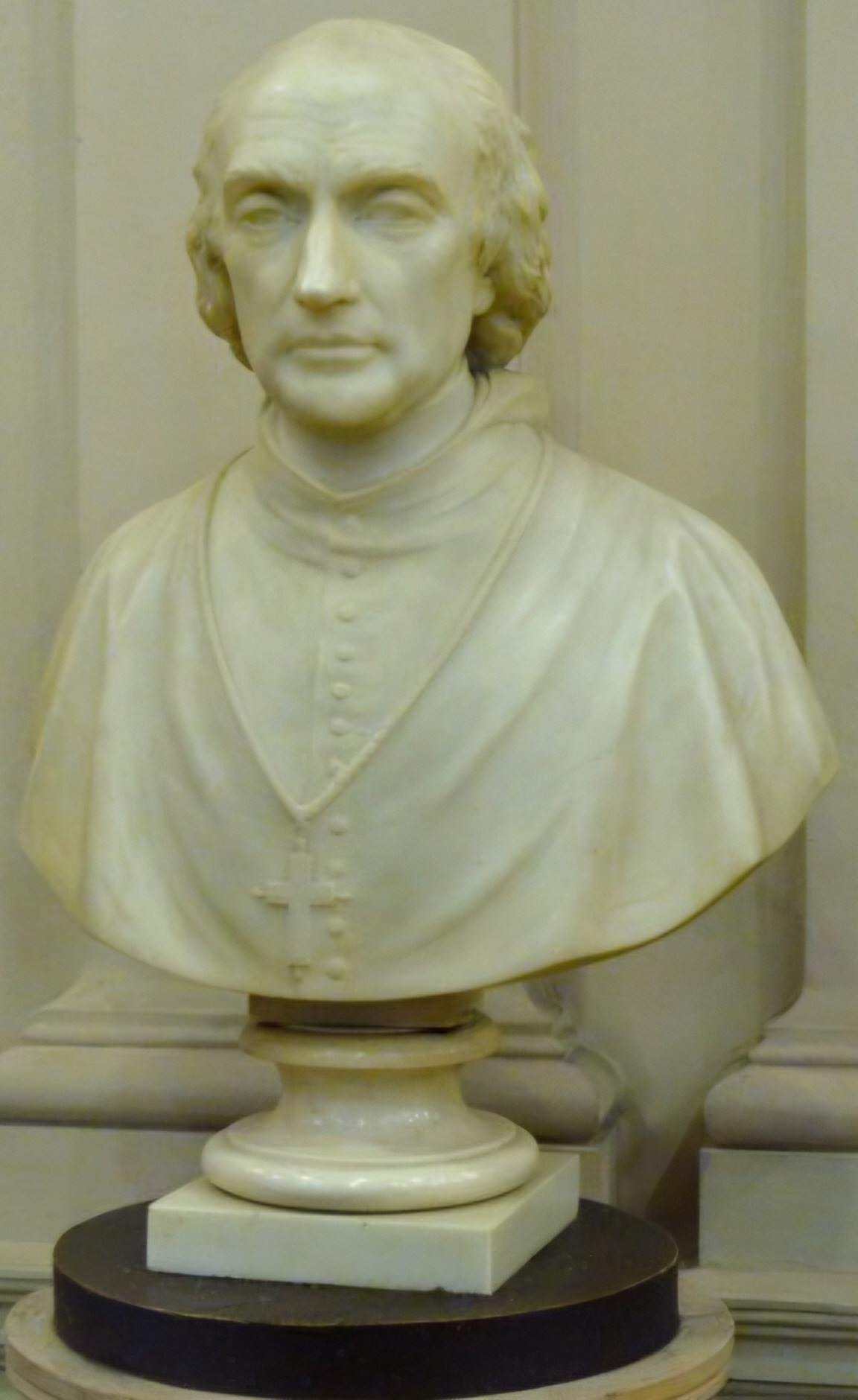 A marble bust of a nineteenth-century cardinal on a plinth in a library.