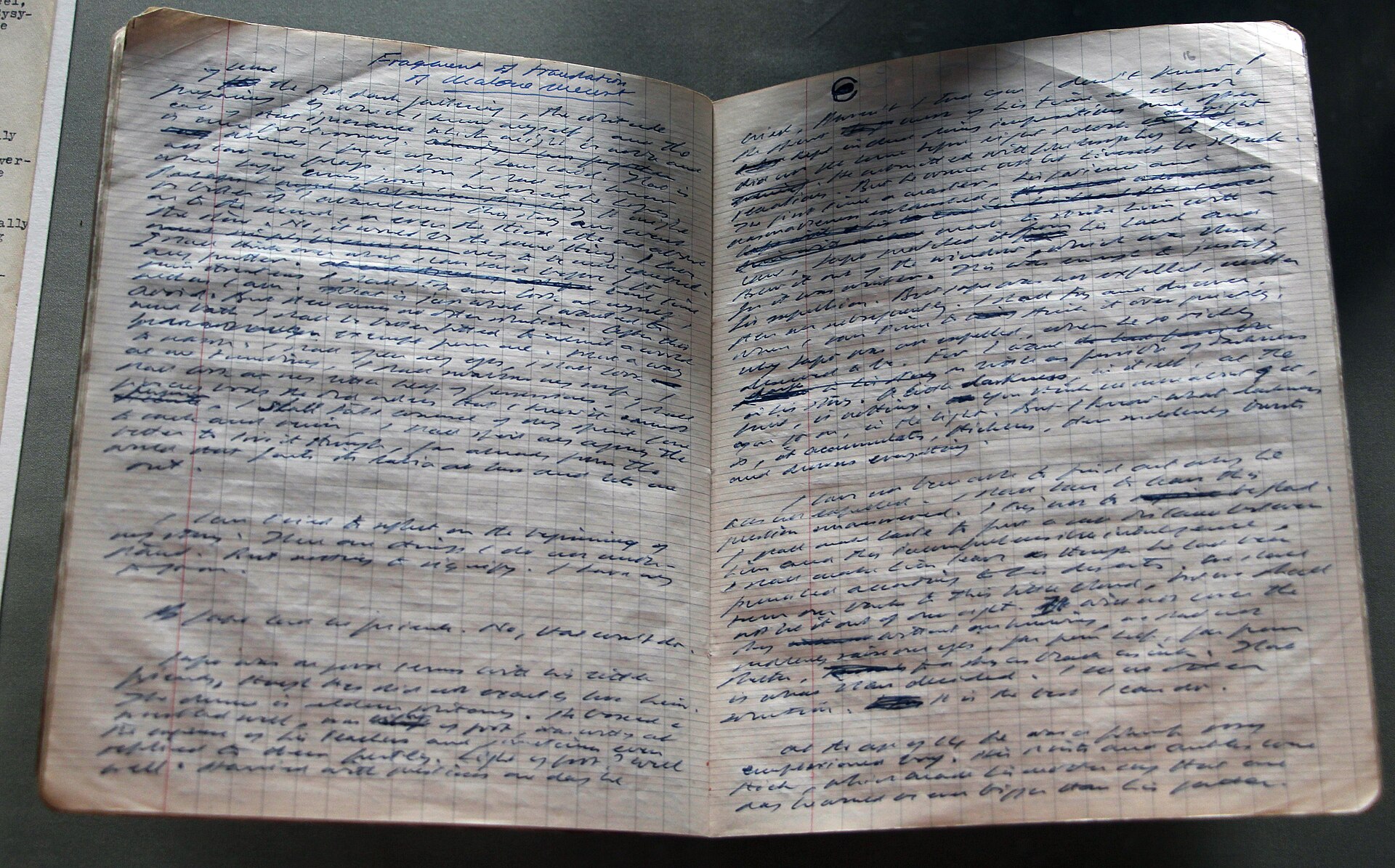 An open exercise book filled with dense handwriting, with whole lines struck through in ink.