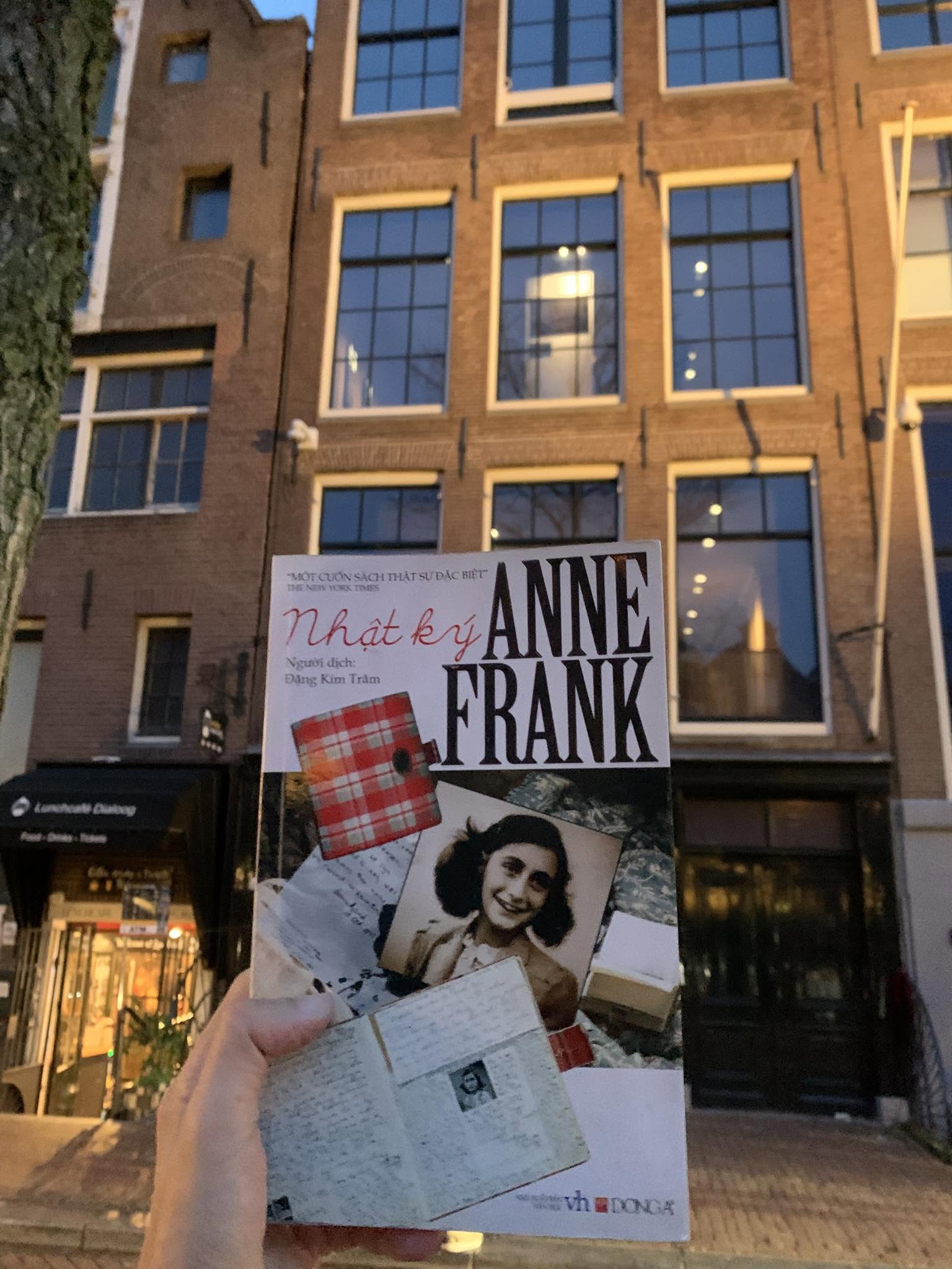 The Vietnamese edition of Anne Frank's diary held up in front of the Anne Frank House at 263 Prinsengracht, Amsterdam