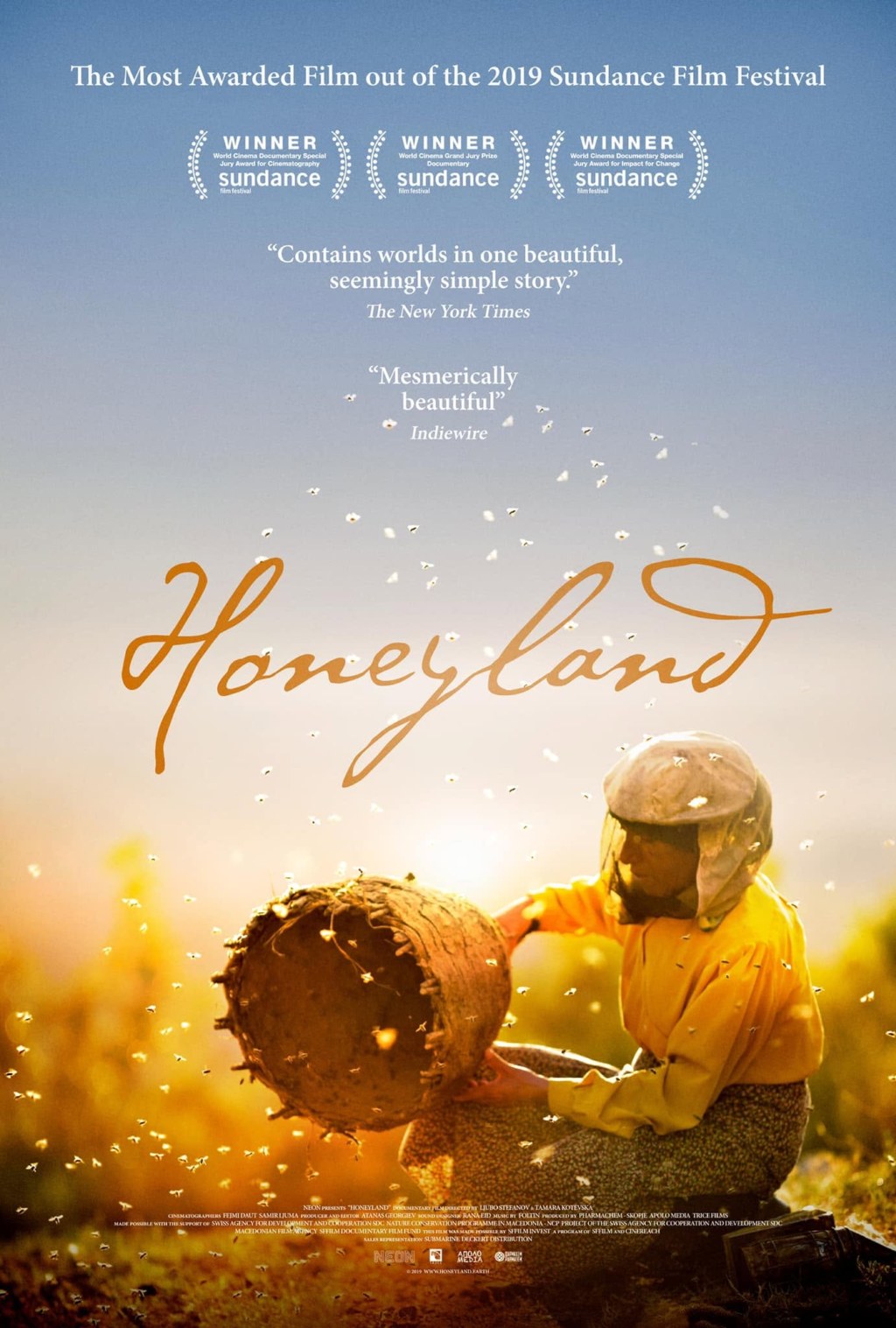 The poster for the documentary Honeyland (2019): Hatidže in a beekeeper’s veil and a yellow jacket, sitting beside a cylindrical hive of bark in a golden meadow, bees filling the late afternoon light; above her, three Sundance 2019 awards