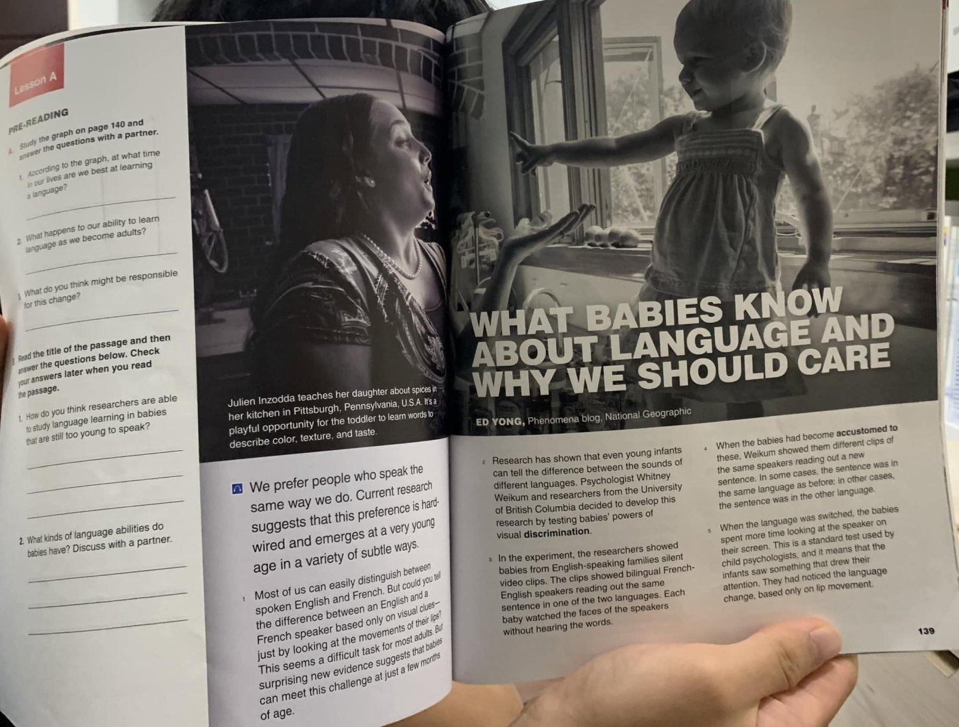 An open textbook spread: on the left, pre-reading questions and a photograph of a mother teaching her daughter in a kitchen; on the right, the large headline “WHAT BABIES KNOW ABOUT LANGUAGE AND WHY WE SHOULD CARE” over a photograph of a toddler by a window, with the byline Ed Yong beneath it