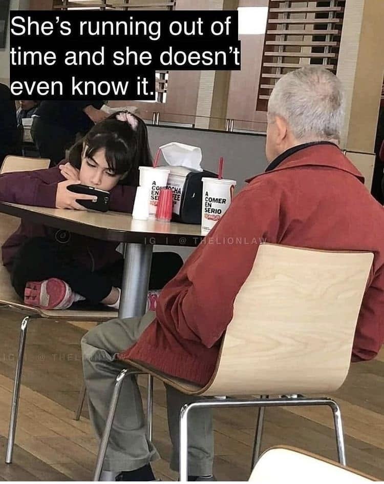 A photograph in a fast-food restaurant: an old man sits with his back to the camera, and across from him a girl slumps over the table with her eyes on her phone; across the top of the picture are the words “She’s running out of time and she doesn’t even know it.”