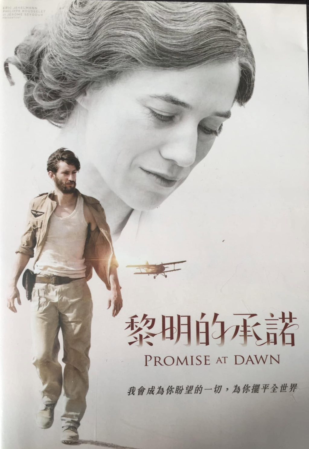 A film poster: a young man in a faded army jacket walking forward, behind him the large face of a grey-haired woman looking down, a biplane between them; at the bottom the title “黎明的承諾 — Promise at Dawn”