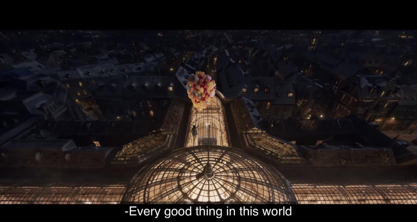 A shot from the trailer for Wonka (2023): a night-time aerial view over a snow-covered city, the lit glass dome of an arcade at the centre, a figure rising into the air with a bunch of coloured balloons; the subtitle at the bottom of the screen reads “Every good thing in this world”